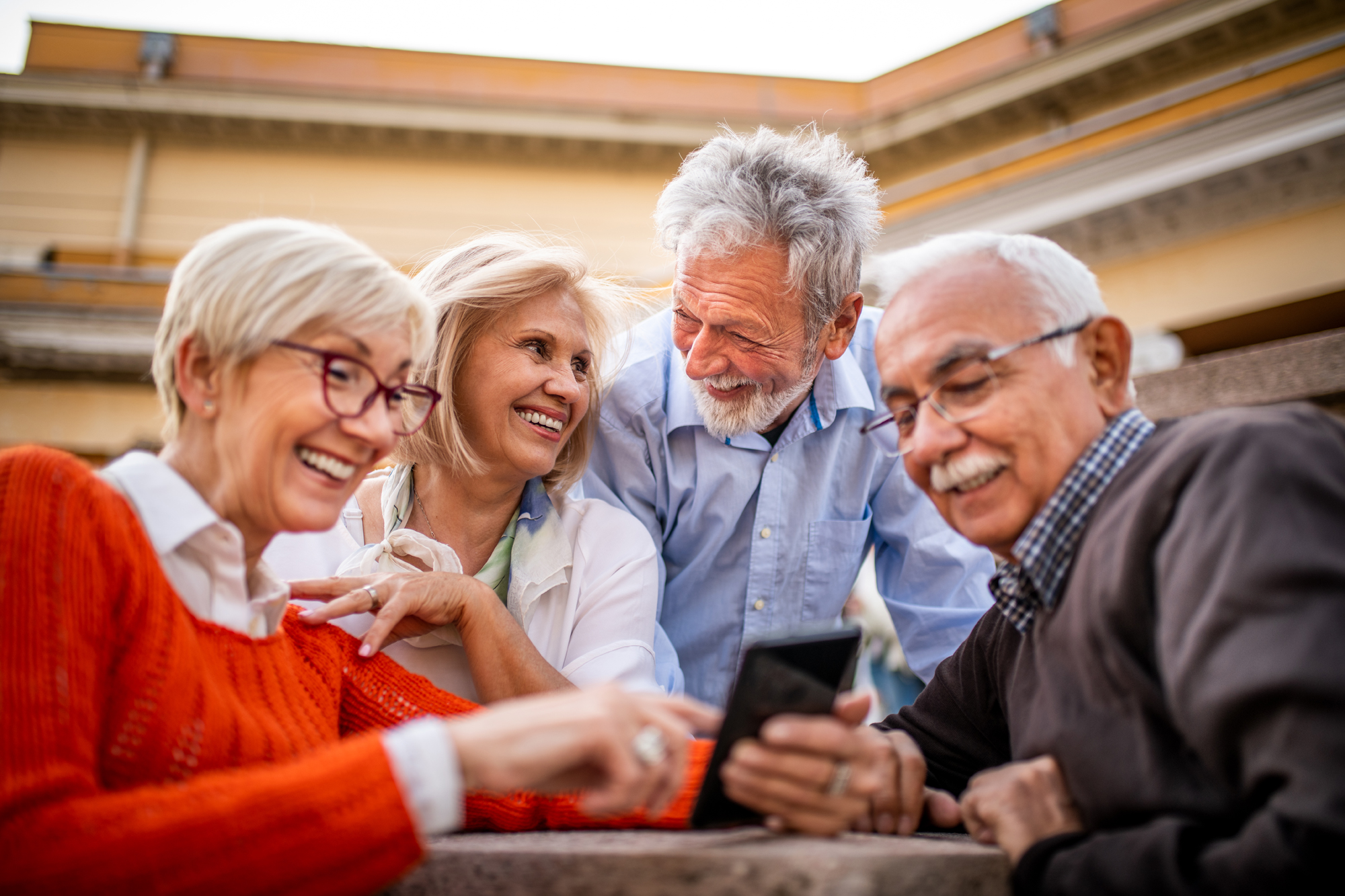 Vie lachende Senior:innen blicken auf ein Smartphone