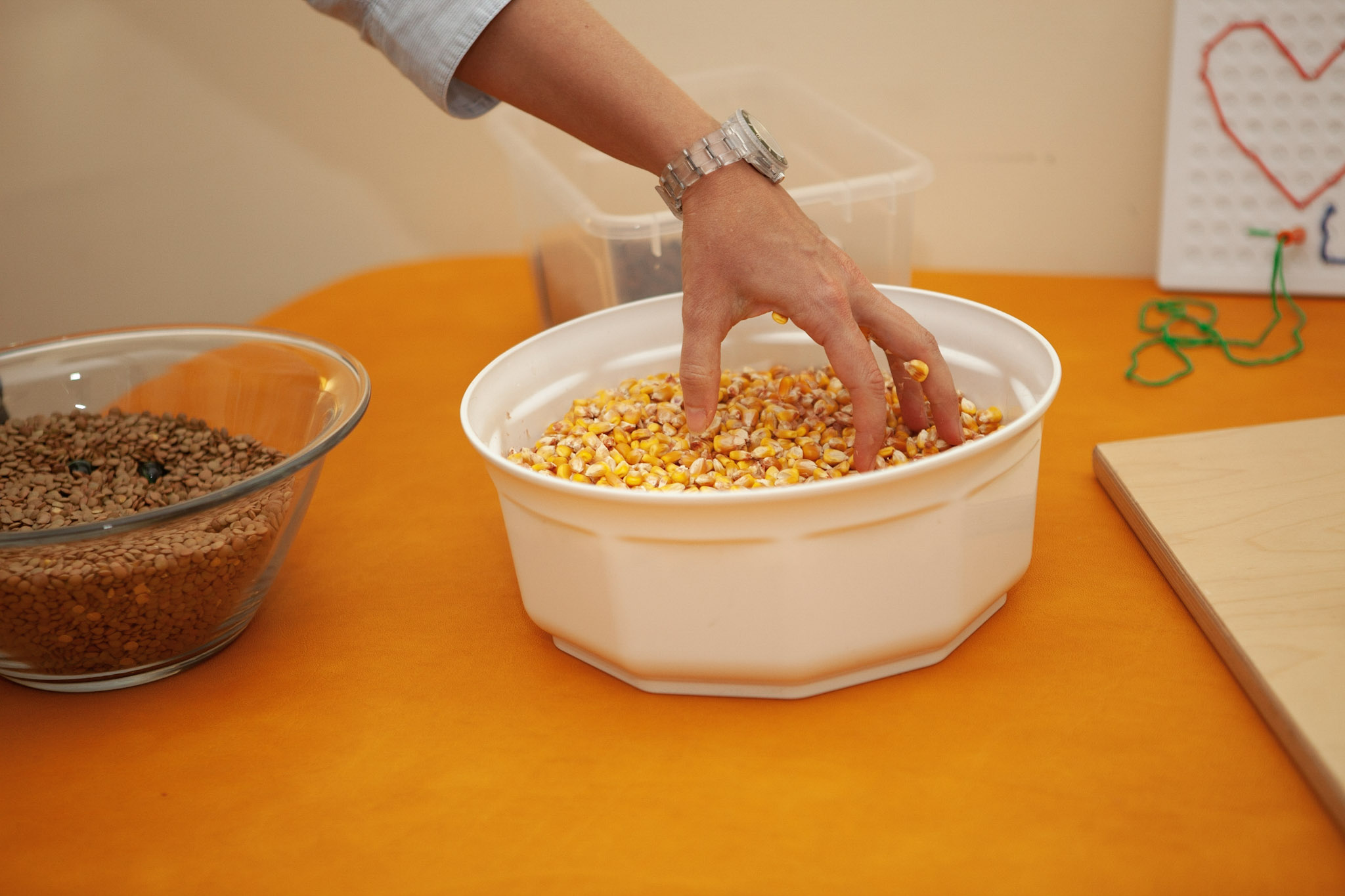 Eine Hand greift nach trockenen Maiskörnern in einer Schüssel