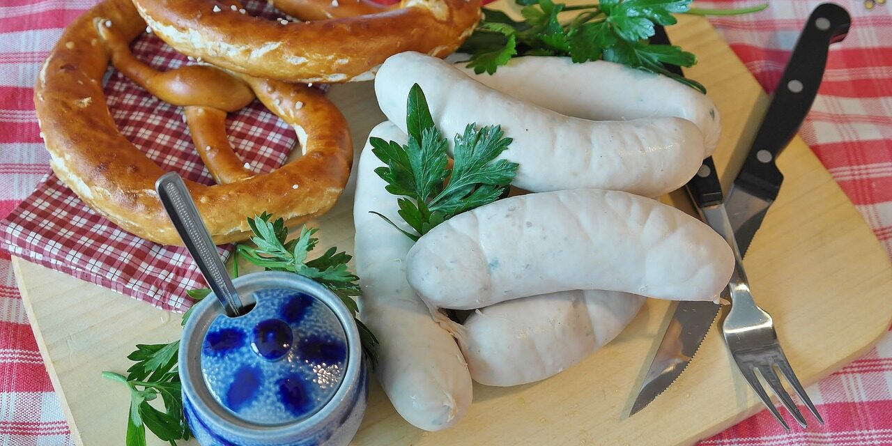 Weißwürste und Brezen auf einem Holzbrett