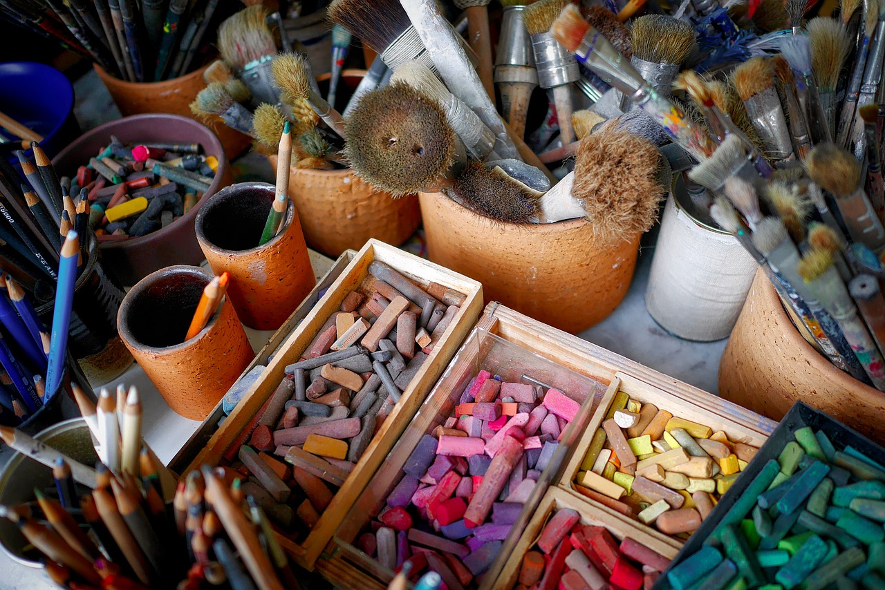 Pinsel, Farben und Kreide auf einem Tisch