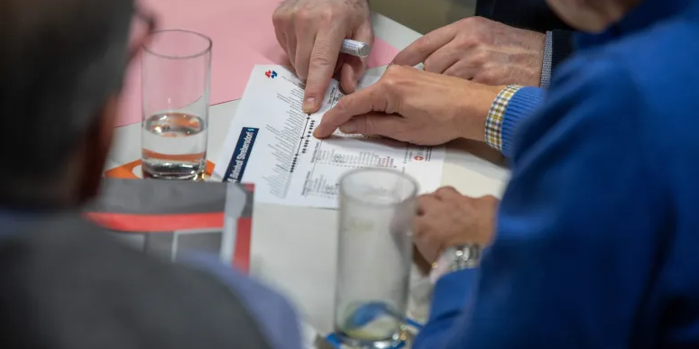 Personen sitzen am Tisch und besprechen ein Dokument
