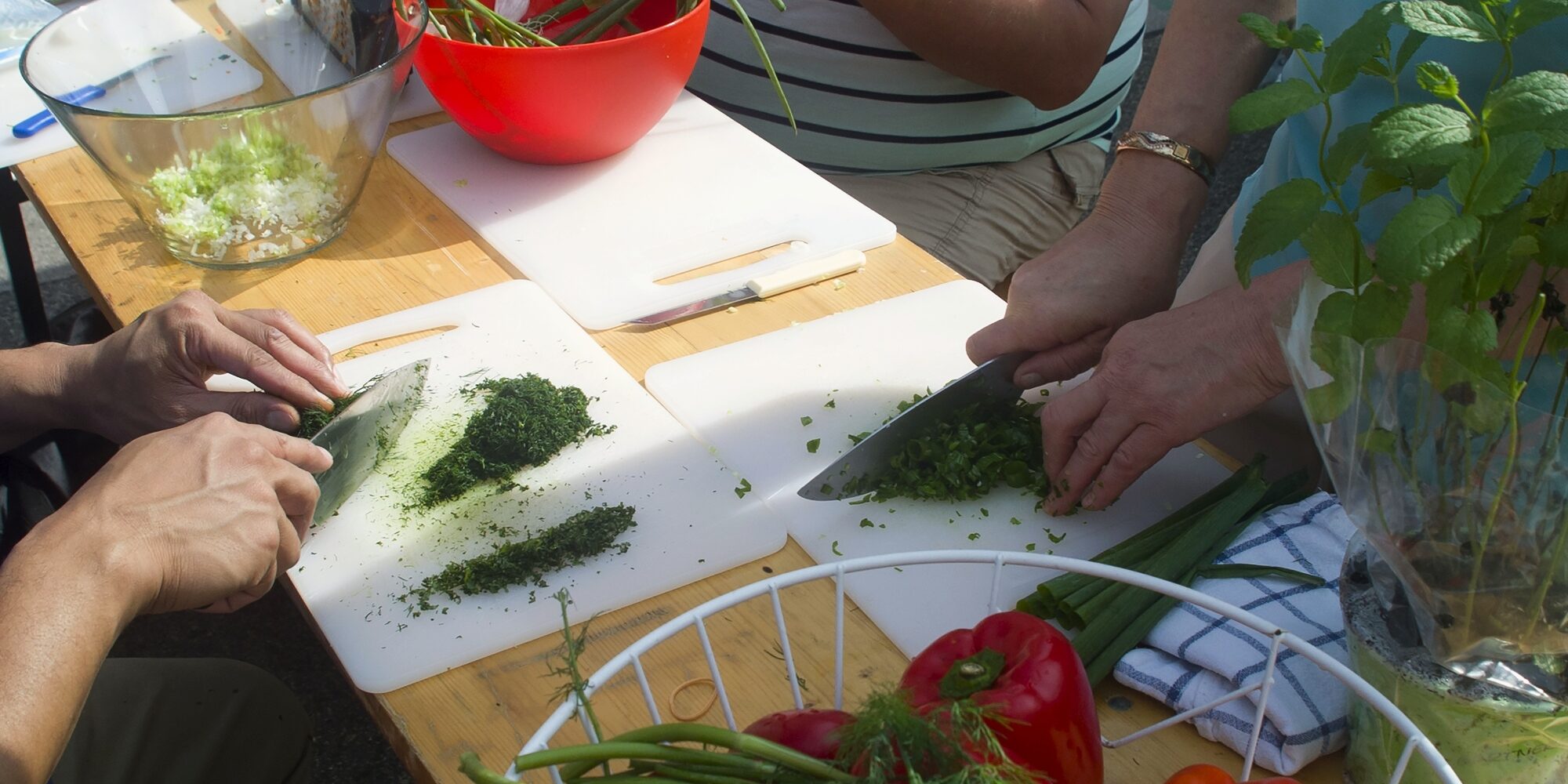 Personen schneiden Kräuter auf einem Brett