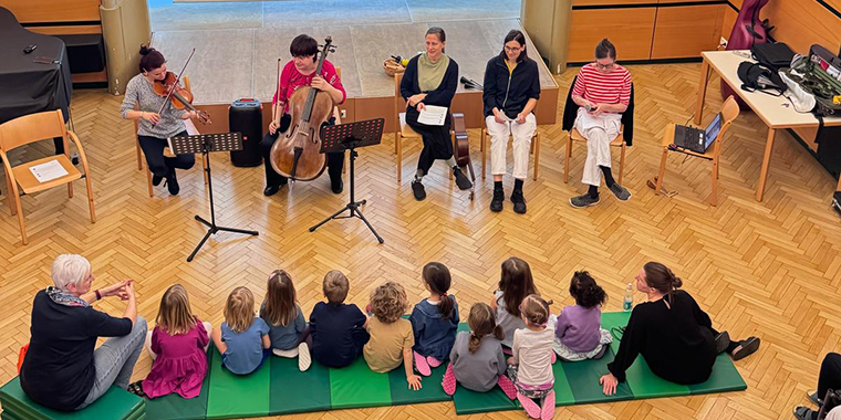 mehrere Musikerinnen und zuhörendes Publikum