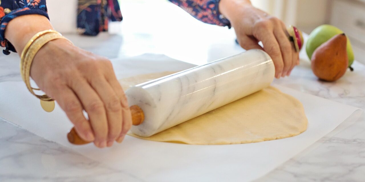 Frau rollt mit Nudelholz Teig aus