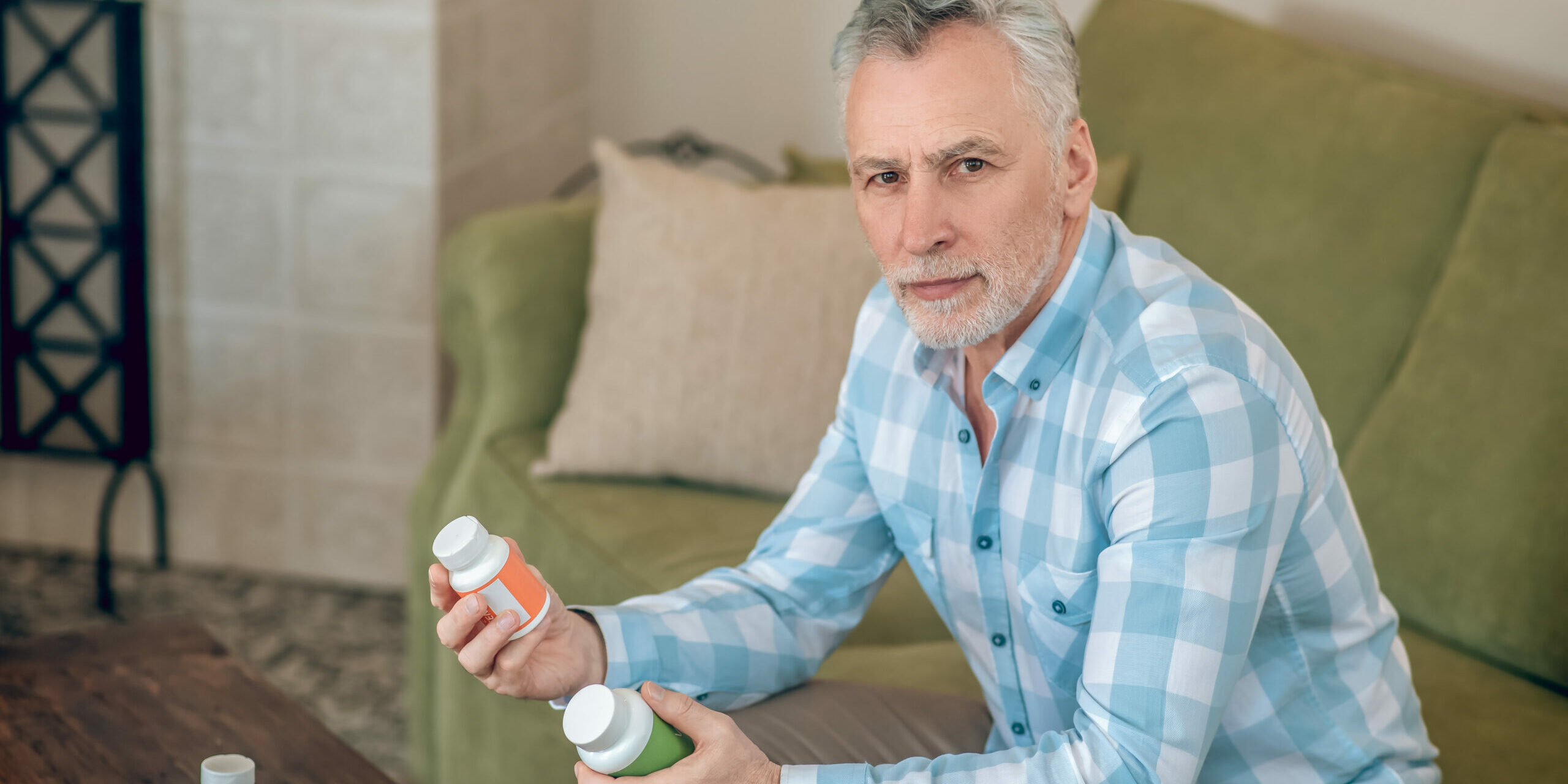 Mann sitzt auf Couch mit Nahrungsergänzungsmitteln