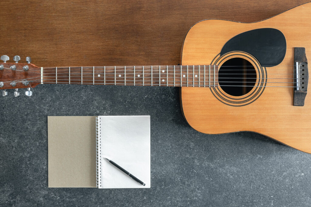 Akustische Gitarre und Notizblock auf neutralem