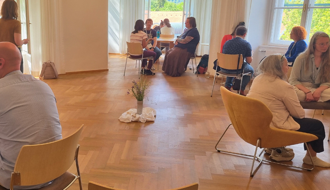 Menschen in einem Raum an Tischen sprechen miteinander